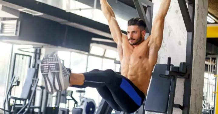 man in a gym performing leg raise exercise